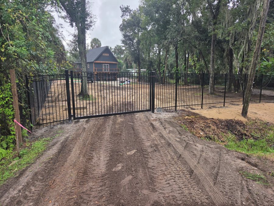 Cleared and graded lot behind a new gate, house at the back