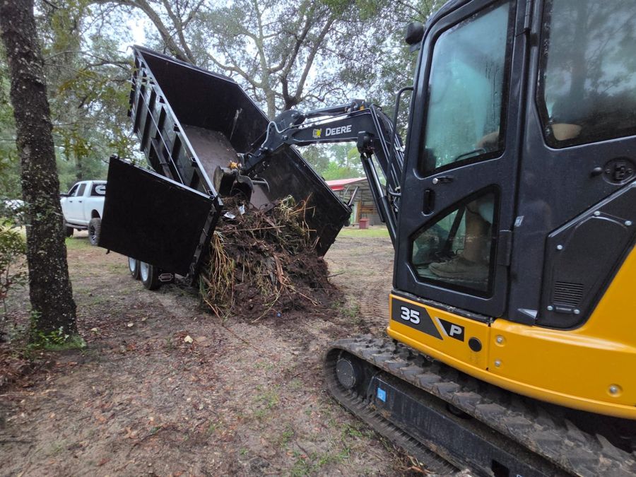 Excavator loading brush into the dump trailer